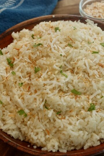 Bowl of fluffy coconut jasmine rice made with full-fat coconut milk and topped with toasted coconut flakes.