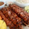 Mango habanero chicken skewers served with coconut jasmine rice, fresh cucumber slices, lime wedges, and ripe mango.