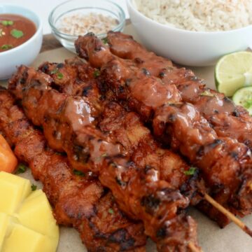 Mango habanero chicken skewers served with coconut jasmine rice, fresh cucumber slices, lime wedges, and ripe mango.