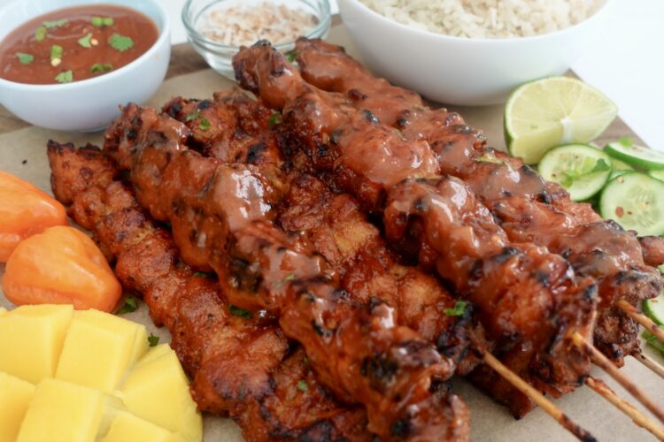 Mango habanero chicken skewers served with coconut jasmine rice, fresh cucumber slices, lime wedges, and ripe mango.