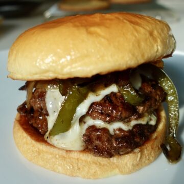 Philly cheesesteak burger with double beef patties, creamy cheese sauce, peppers and onions.