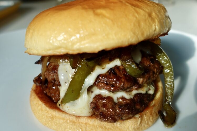 Philly cheesesteak burger with double beef patties, creamy cheese sauce, peppers and onions.