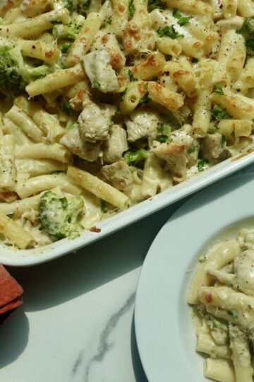 Creamy chicken and broccoli ziti topped with melted mozzarella cheese in a baking dish.