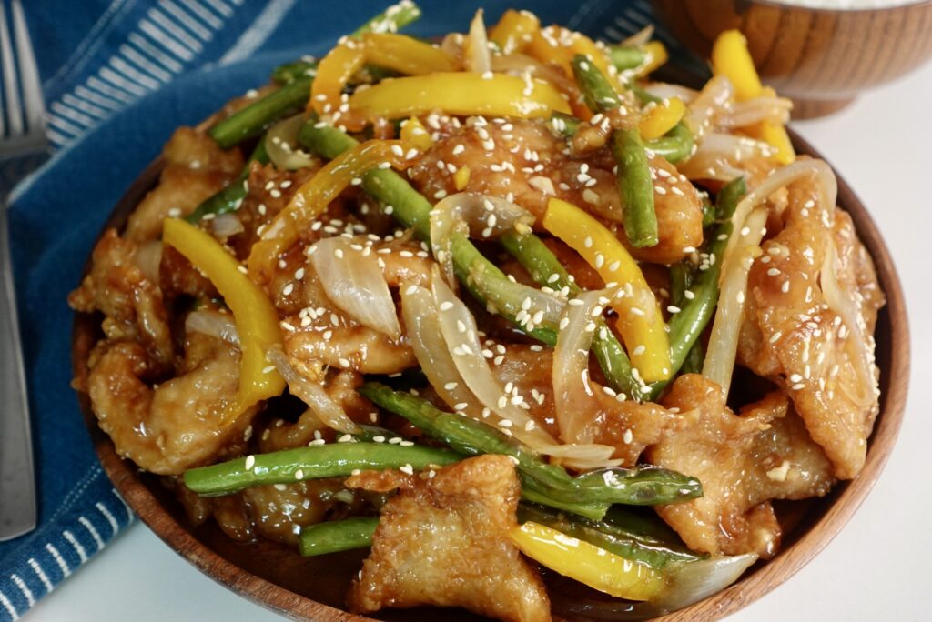 Lightly battered crispy chicken breast tossed with crisp green beans and yellow bell peppers in a glossy homemade honey sesame sauce and finished with toasted sesame seeds.