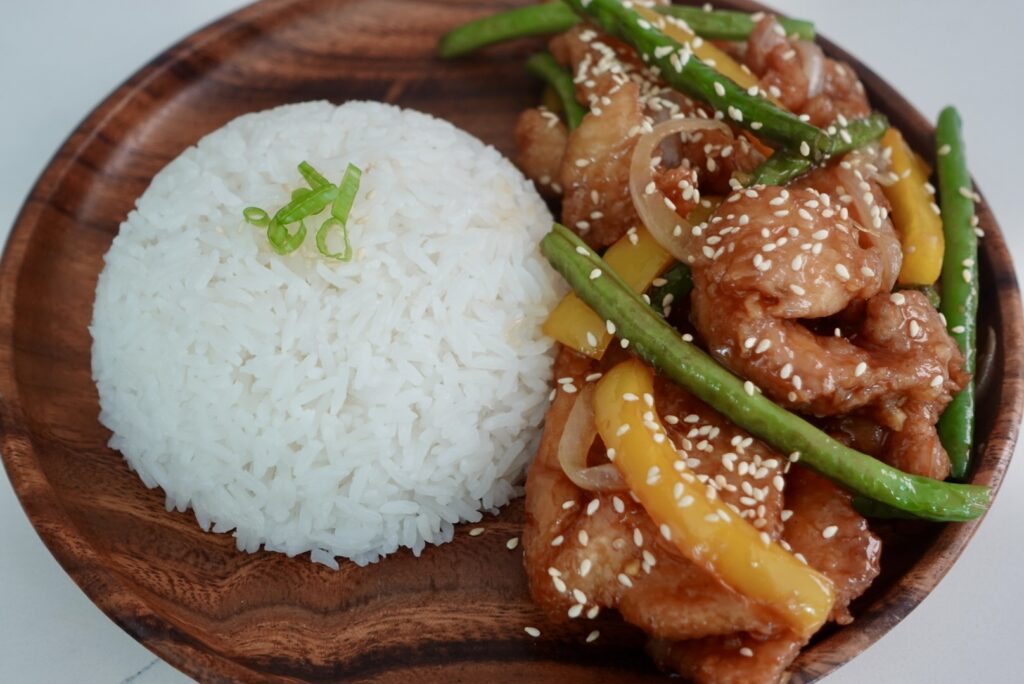 honey sesame chicken breast with green beans and yellow bell peppers served over jasmine rice.