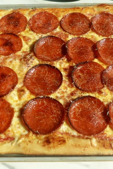 Homemade sheet pan pepperoni pizza with mozzarella, Parmesan, and tomato sauce on a golden chewy crust.