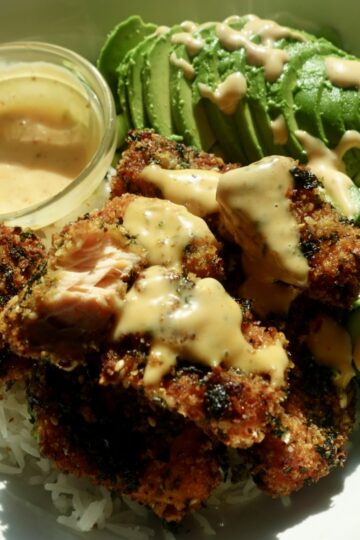 Seaweed-crusted salmon bites with a golden, crunchy panko and roasted seaweed coating, served over white rice with cucumber, edamame and bang bang dipping sauce.